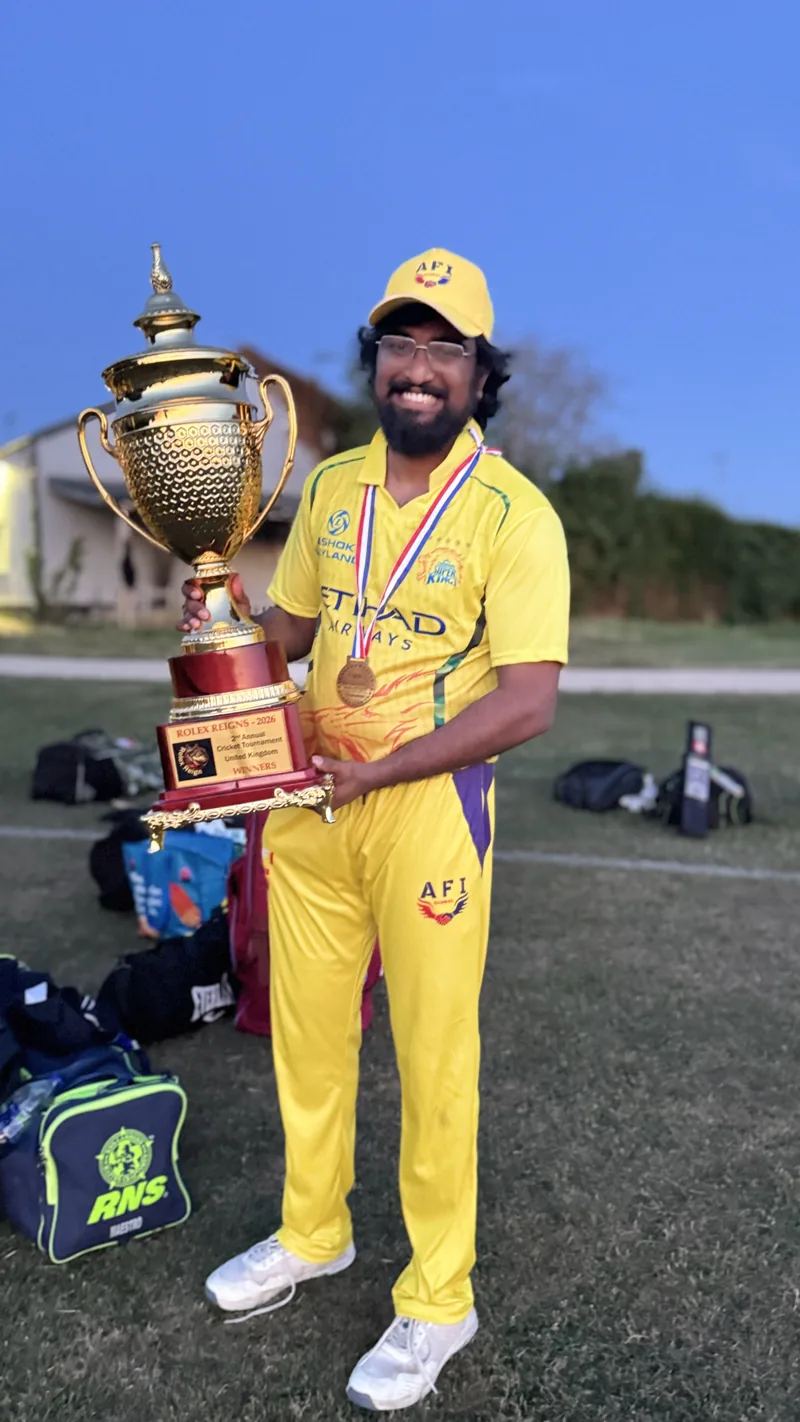Dhamotharan holding a cricket trophy